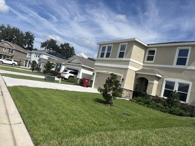 Green, freshly cut front lawn of a two-story home