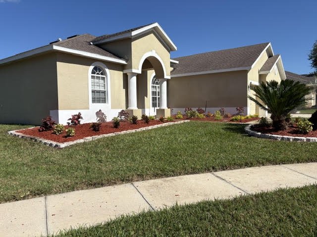 After: finished front yard with edged beds, red mulch and green lawn