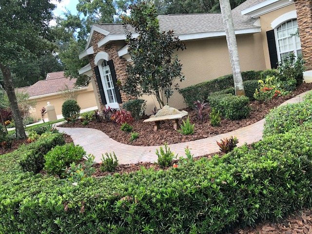 Landscaped front yard with trimmed hedges, fresh mulch beds and a brick walkway
